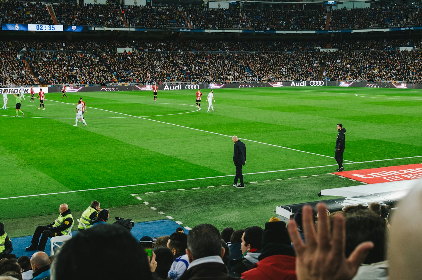 Des joueurs de soccer s'affrontent sur un terrain vert dans un stade bondé.