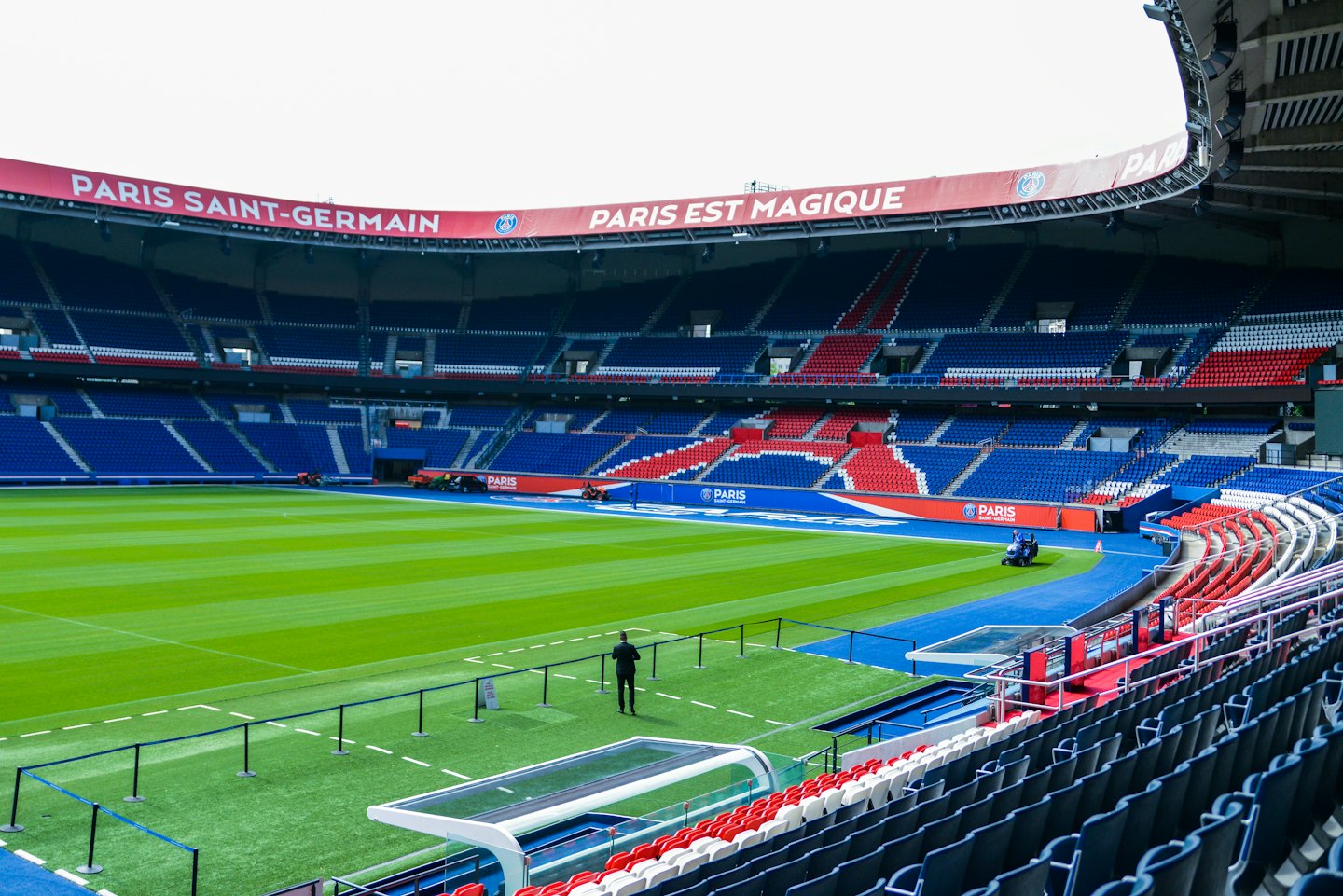 Une personne traverse le terrain d'un grand stade de football.