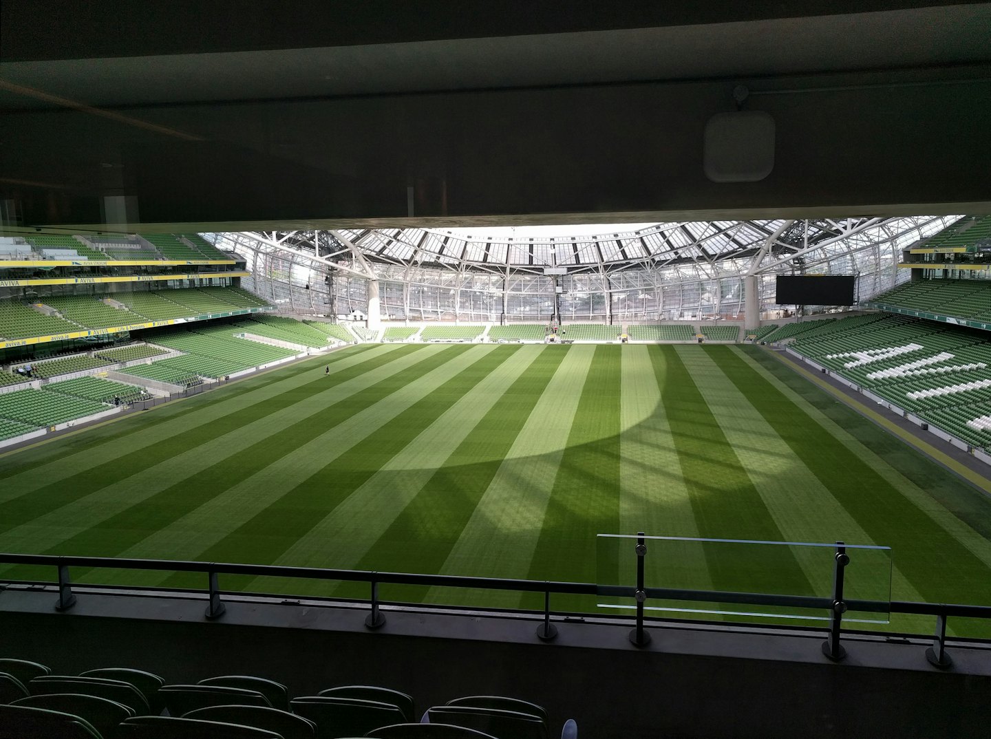 Stade sportif moderne avec pelouse verte et sièges vides.