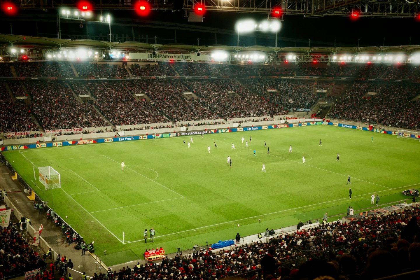 Des joueurs de soccer s'affrontent sur un terrain de stade devant une foule nombreuse.
